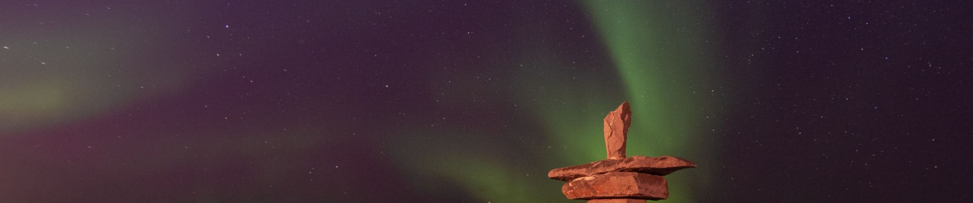 statues-inuit-en-pierre-sous-aurores-boreales-canada