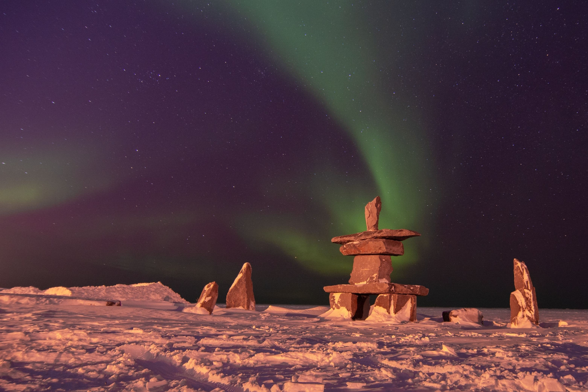 statues-inuit-en-pierre-sous-aurores-boreales-canada